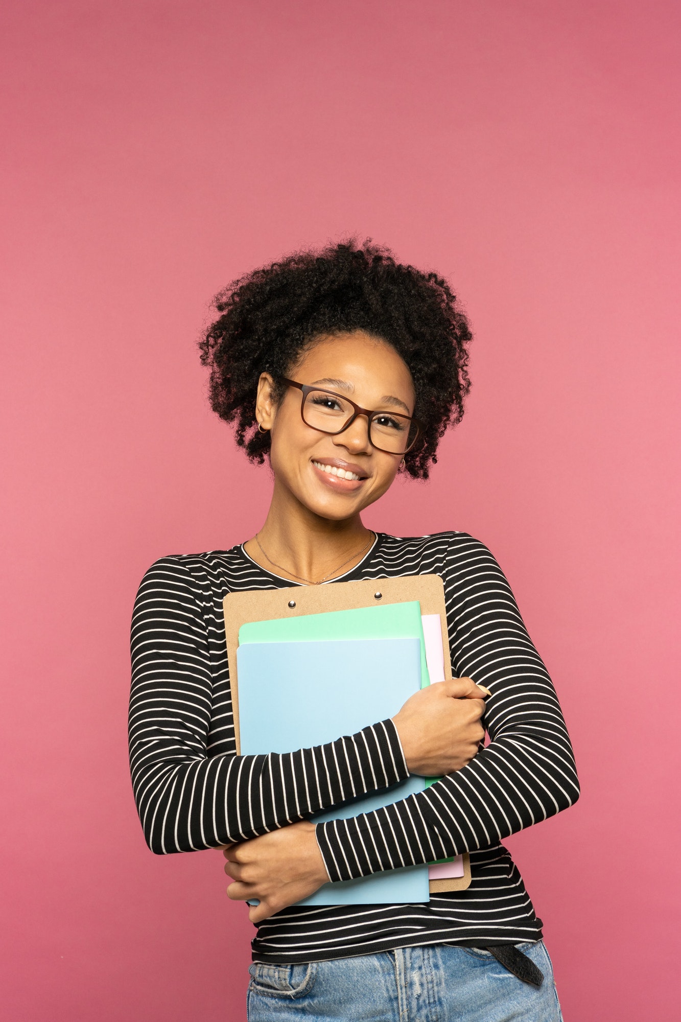 Happy Afro-American tutor or teacher woman isolated on pink studio wall. Education in high school
